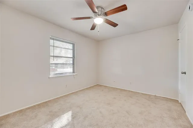 an empty room with a window and a ceiling fan