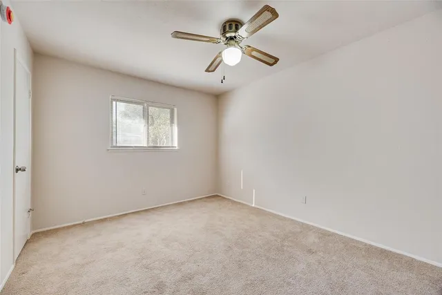 an empty room with a window and a fan