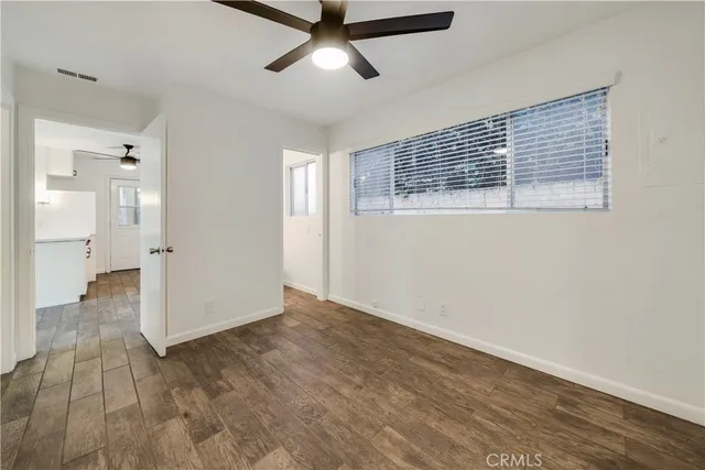 a view of empty room with wooden floor and windows