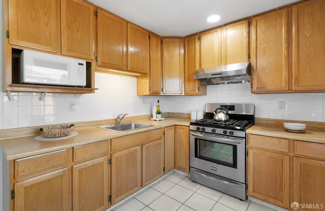 a kitchen with stainless steel appliances granite countertop white cabinets a stove a sink and dishwasher