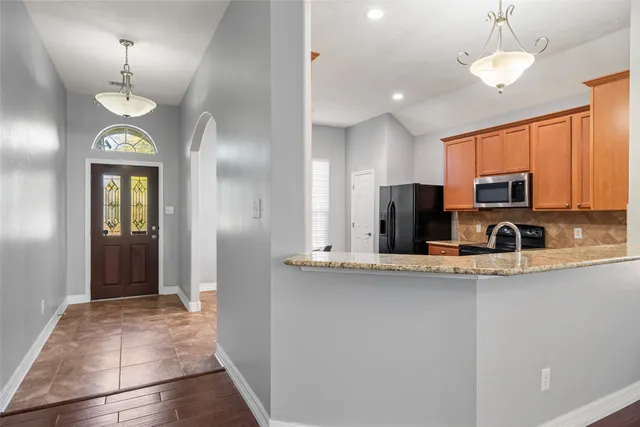 a view of kitchen with stainless steel appliances granite countertop stove top oven and refrigerator