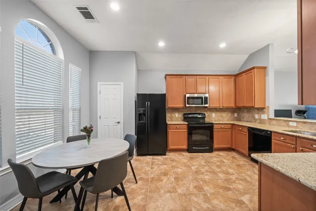 a kitchen with stainless steel appliances granite countertop a stove a refrigerator a kitchen island a sink dishwasher a dining table and chairs with wooden floor