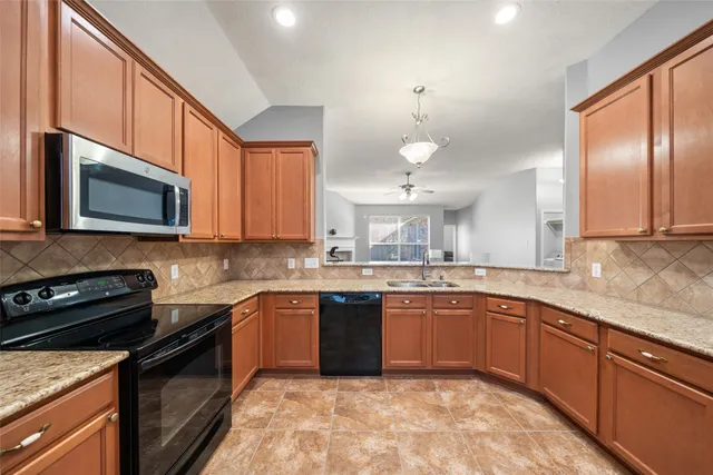 a kitchen with stainless steel appliances granite countertop wooden cabinets a stove a sink and a microwave