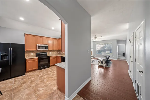 a kitchen with stainless steel appliances kitchen island granite countertop a refrigerator a stove a sink a dining table and chairs with wooden floor