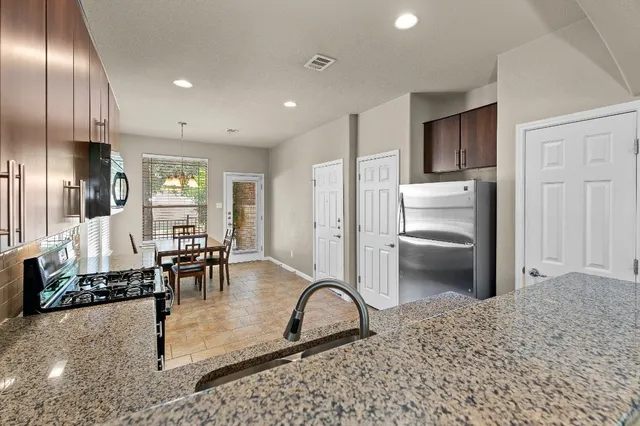 a kitchen with granite countertop a refrigerator and furniture