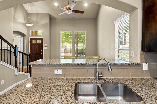 a kitchen with granite countertop a sink a counter top space and cabinets