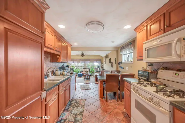 a kitchen with stainless steel appliances kitchen island granite countertop a refrigerator a stove a sink dishwasher and cabinets with wooden floor