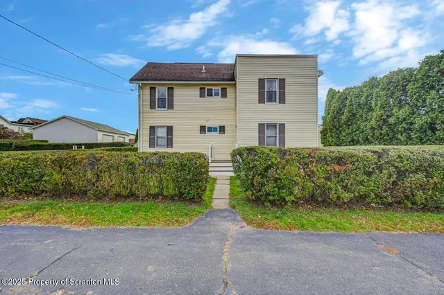 a view of a house with a yard and potted plants