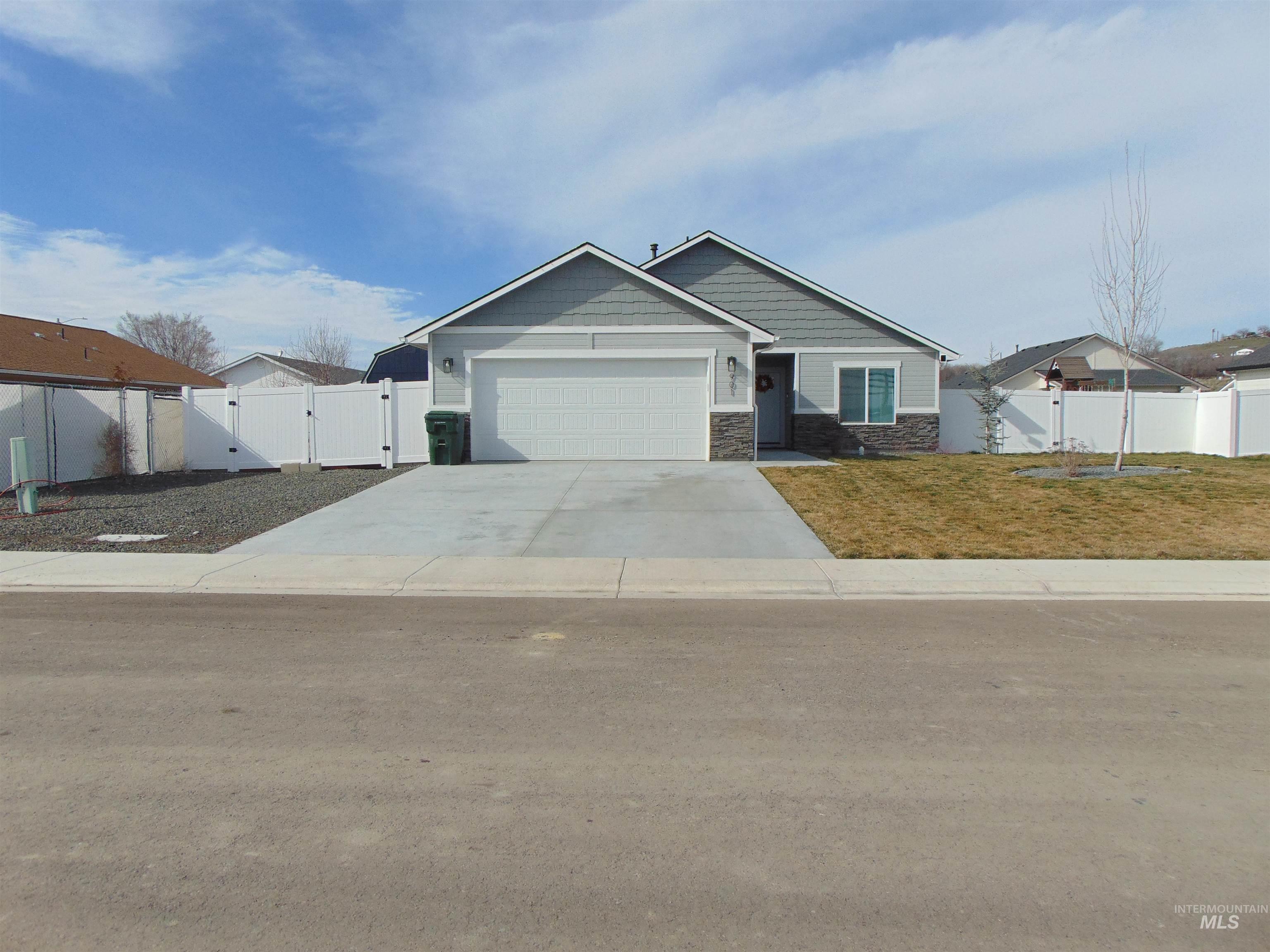 View of front of home with a gate, stone siding, an attached garage, and concrete driveway