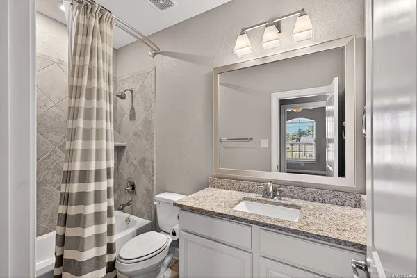 a kitchen with stainless steel appliances granite countertop a sink dishwasher a refrigerator and white cabinets with wooden floor