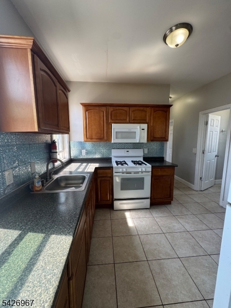 23 Elliott Street Newark, NJ 07104 - Photo 21 of 25 a kitchen with a stove a sink and a microwave