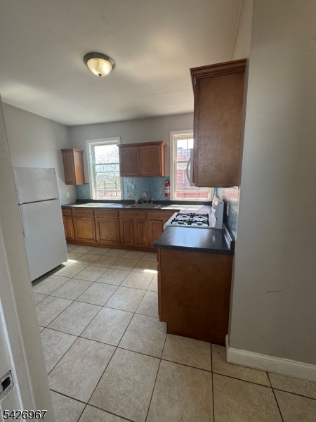 23 Elliott Street Newark, NJ 07104 - Photo 22 of 25 a kitchen with granite countertop a refrigerator a stove a microwave and a counter top space