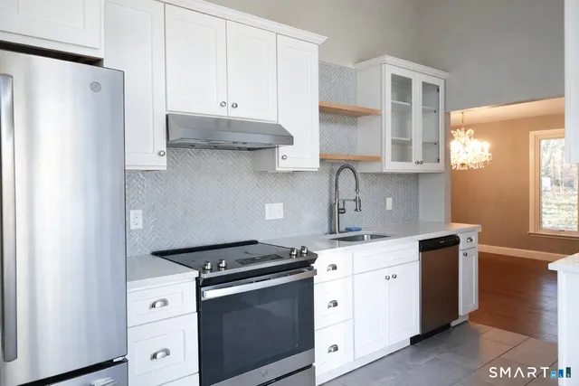a kitchen with stainless steel appliances a stove a sink and white cabinets