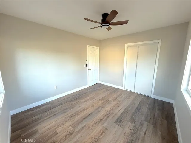a view of a room with wooden floor and a ceiling fan