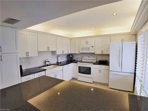 a kitchen with granite countertop white cabinets and white appliances