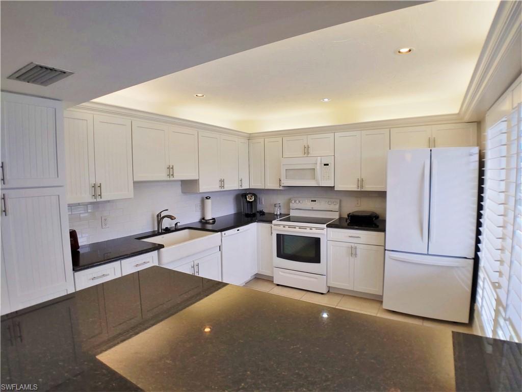108 Penny Lane, Unit 4 Naples, FL 34112 - Photo 16 of 33 a kitchen with granite countertop white cabinets and white appliances
