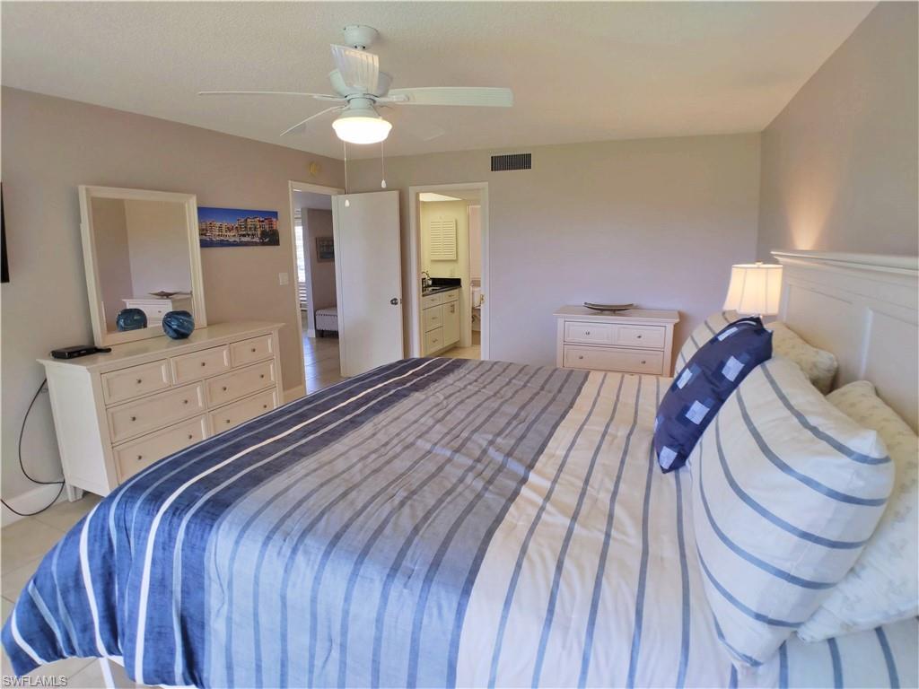 108 Penny Lane, Unit 4 Naples, FL 34112 - Photo 25 of 33 a bedroom with a bed and a chandelier