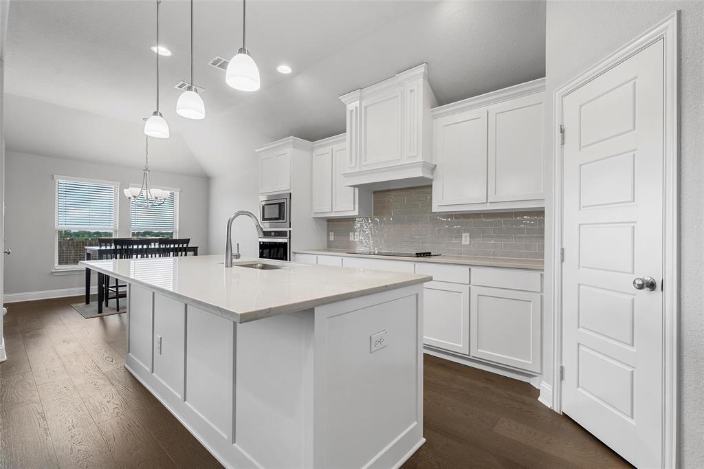 1904 Angelus Street Waco, TX 76712 - Photo 7 of 24 Kitchen featuring decorative backsplash, dark wood finished floors, light countertops, white cabinets, and an island with sink