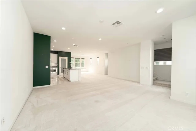 a large kitchen with stainless steel appliances kitchen island a large counter top a refrigerator and a sink