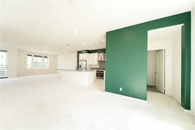 a large white kitchen with kitchen island a sink white cabinets and stainless steel appliances