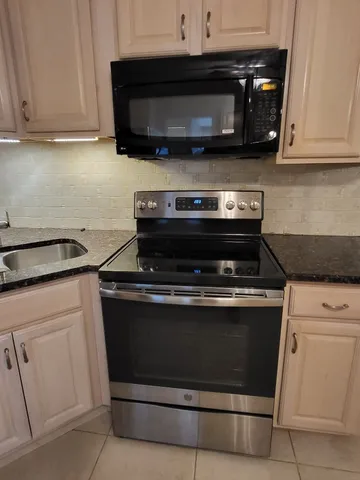 a kitchen with granite countertop white cabinets and stainless steel appliances