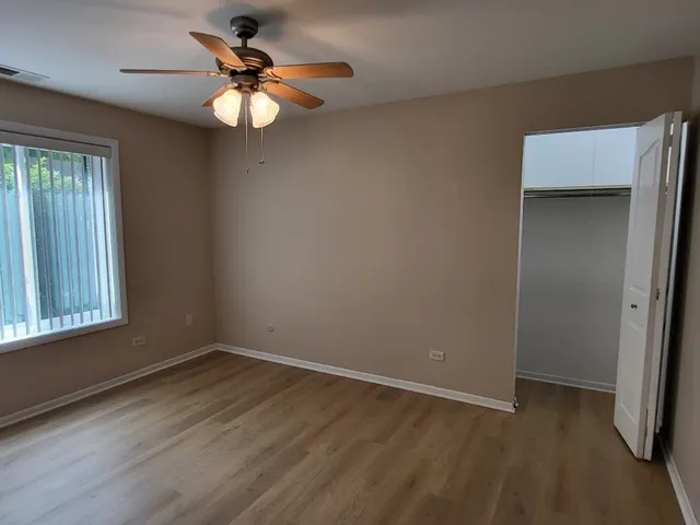 an empty room with wooden floor fan and windows