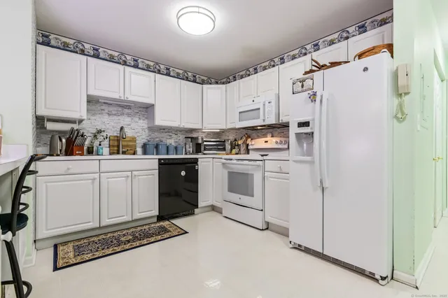 a kitchen with white cabinets and white appliances