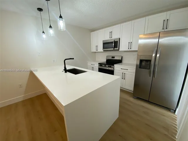 a kitchen that has a microwave a sink and a refrigerator