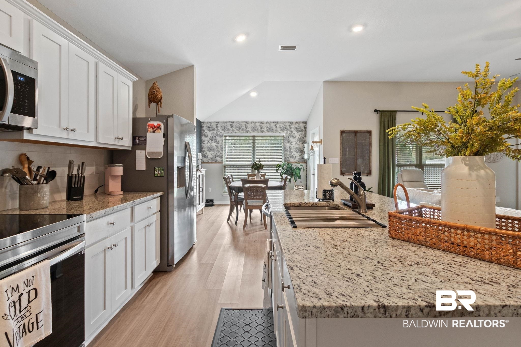 1203 Hayward Loop Foley, AL 36535 - Photo 11 of 41 Kitchen with stainless steel appliances, white cabinets, vaulted ceiling, light stone countertops, and light wood finished floors