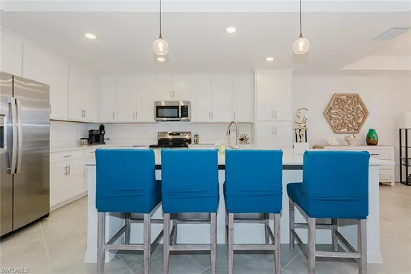 a kitchen with stainless steel appliances granite countertop a sink a stove a refrigerator cabinets a dining table and chairs