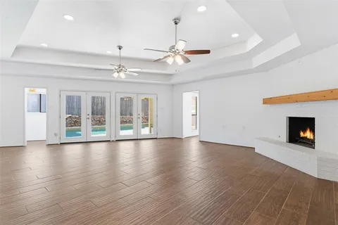 an empty room with wooden floor chandelier entryway and windows