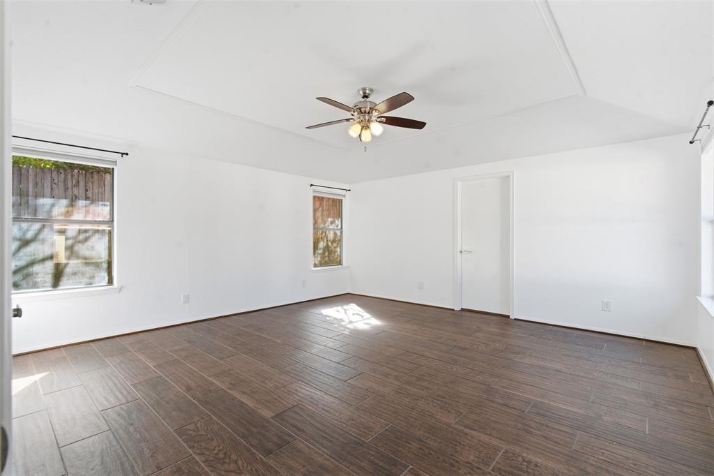 2201 Mistletoe Boulevard Fort Worth, TX 76110 - Photo 13 of 31 an empty room with wooden floor chandelier fan and windows