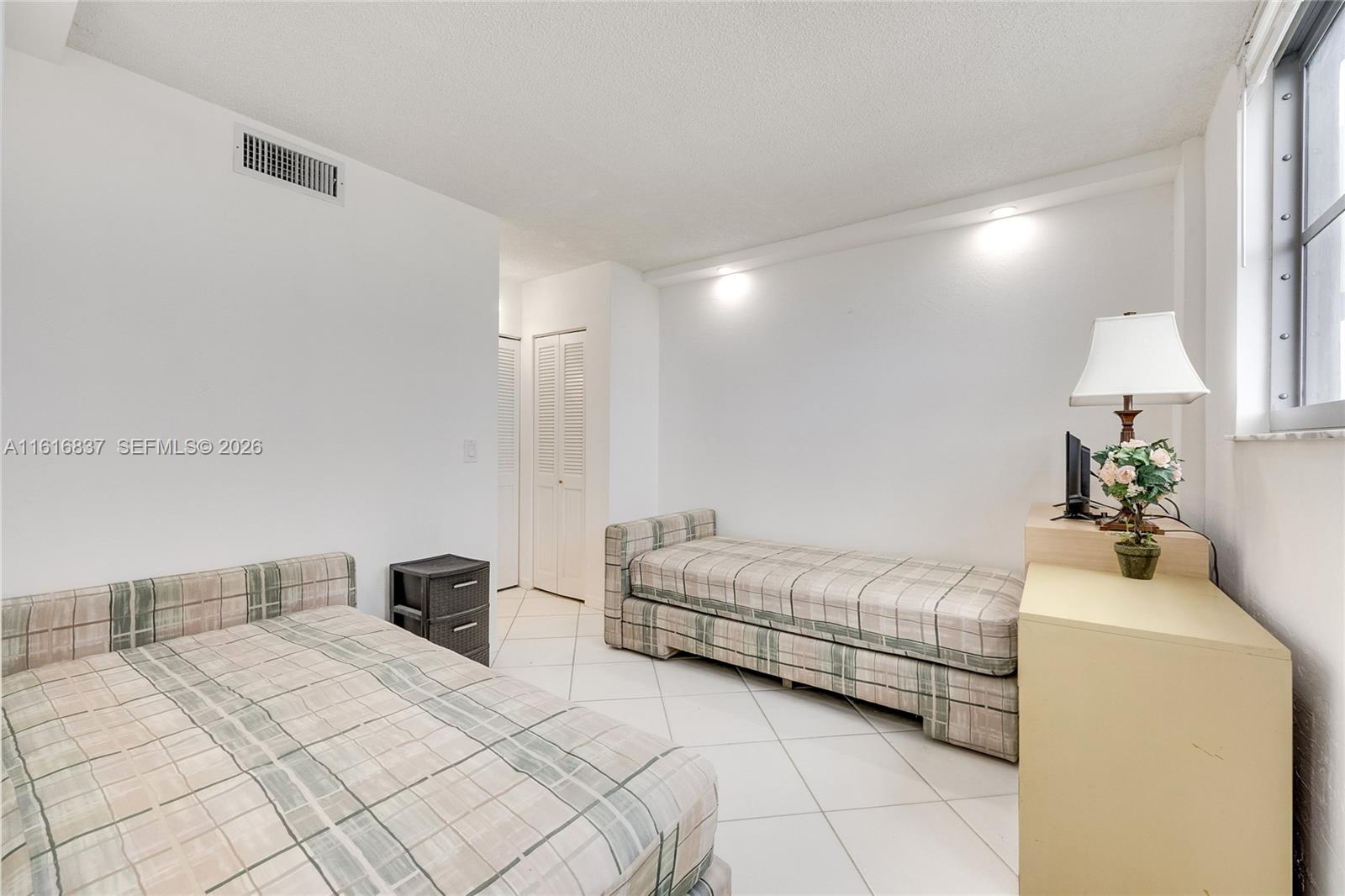 9273 Collins Avenue, Unit 507 Surfside, FL 33154 - Photo 13 of 22 a bedroom with a bed and a night stand