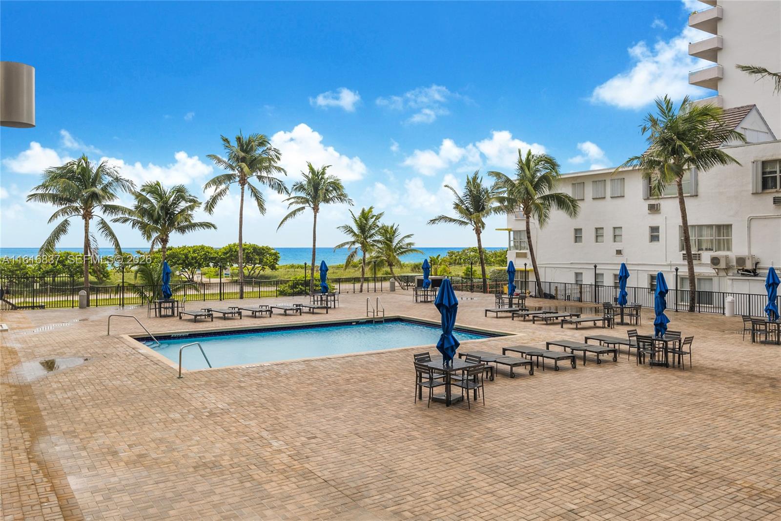 9273 Collins Avenue, Unit 507 Surfside, FL 33154 - Photo 16 of 22 a view of a swimming pool with a table and chairs