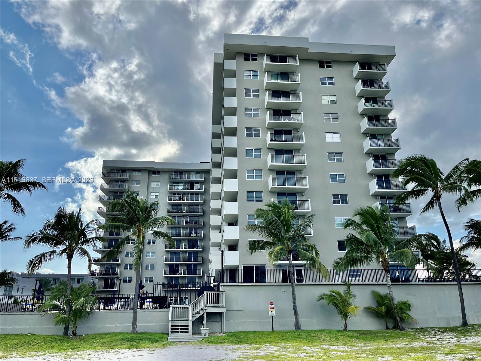 9273 Collins Avenue, Unit 507 Surfside, FL 33154 - Photo 20 of 22 a front view of a multi story building with yard