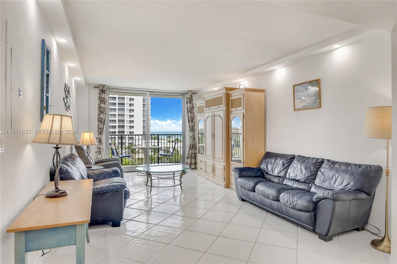 9273 Collins Avenue, Unit 507 Surfside, FL 33154 - Photo 5 of 22 a living room with furniture and a lamp