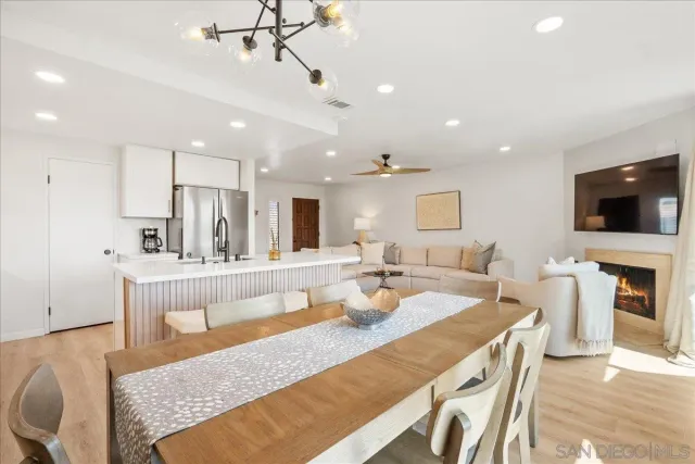 a large living room with stainless steel appliances granite countertop furniture a fireplace a flat screen tv and a lamp