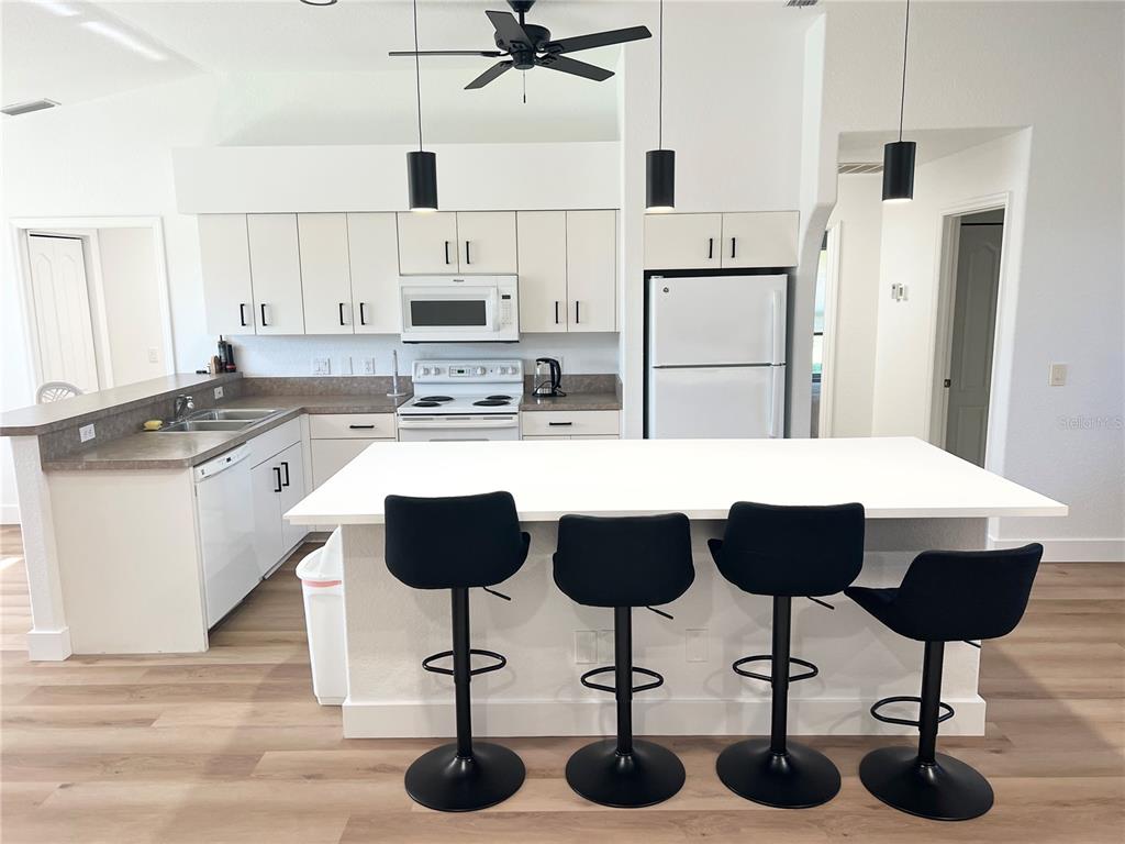 255 Medalist Road Rotonda West, FL 33947 - Photo 2 of 21 a kitchen with stainless steel appliances kitchen island granite countertop a table chairs sink and cabinets