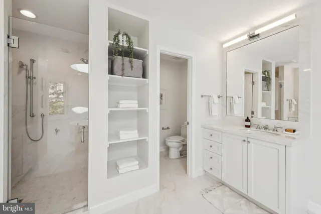 a bathroom with a glass shower door a sink and a mirror