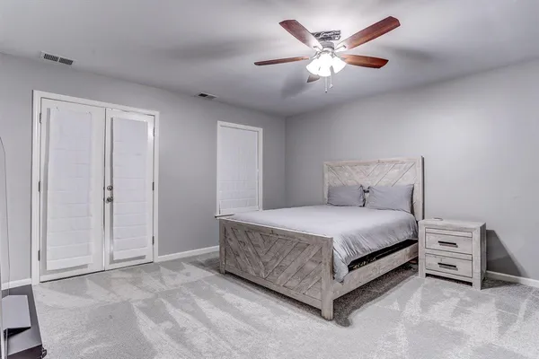 a spacious bedroom with a bed and a ceiling fan