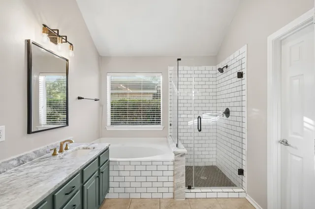 a bathroom with a sink vanity granite tub shower and a mirror