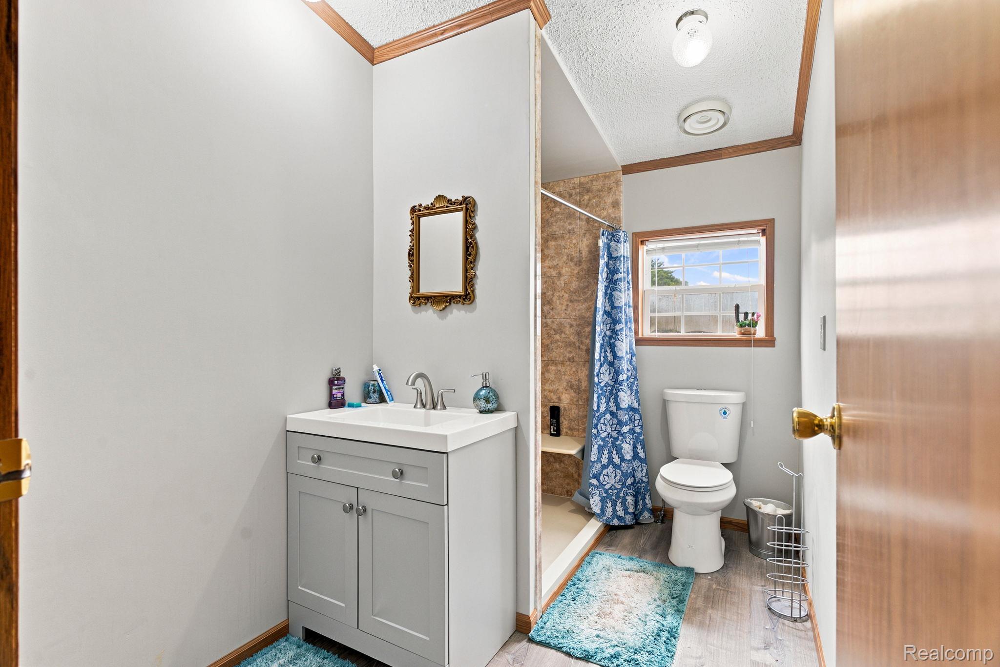 2390 Lakeshore Road Applegate, MI 48401 - Photo 29 of 97 Bathroom featuring a vanity with dual-sink configuration and ample storage, ceramic tile flooring with decorative accent runner, walk-in shower with tile surround, and natural light from a window