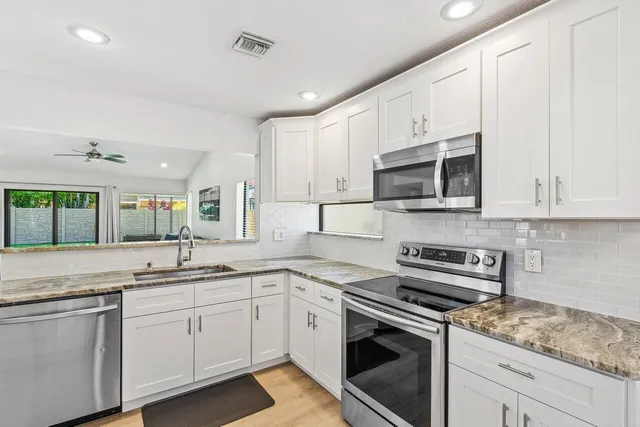 a kitchen with stainless steel appliances granite countertop white cabinets a sink and dishwasher