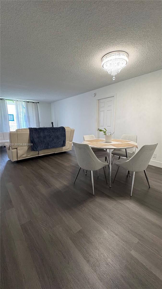 299 Northwest 52nd Terrace, Unit PHX Boca Raton, FL 33487 - Photo 24 of 29 a living room with a table chairs and a wooden floor