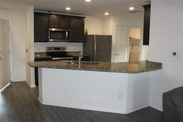 a kitchen with stainless steel appliances granite countertop a refrigerator a stove top oven a sink and dishwasher