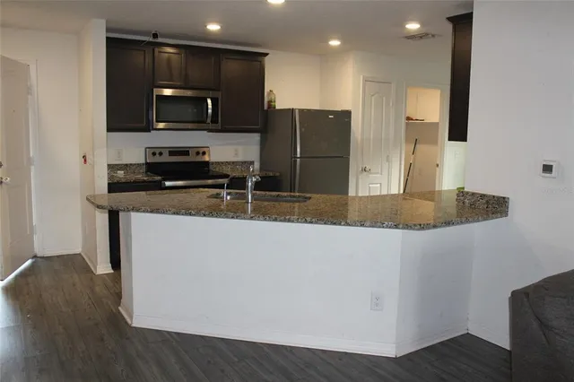 a kitchen with stainless steel appliances granite countertop a refrigerator a stove top oven a sink and dishwasher