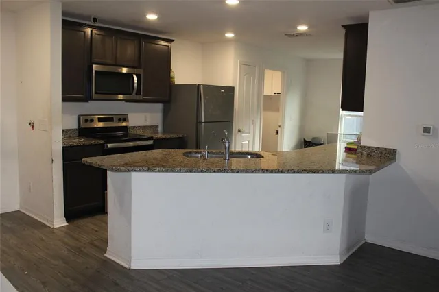 a kitchen with granite countertop a refrigerator and a stove top oven