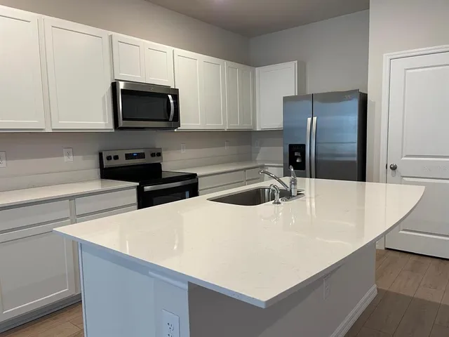 a view of a kitchen with a sink and dishwasher a refrigerator with white cabinets