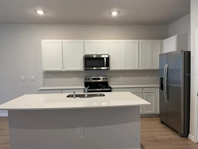 a kitchen with a sink white cabinets and stainless steel appliances