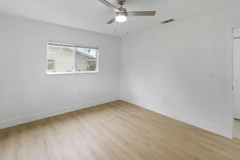 an empty room with a window and ceiling fan